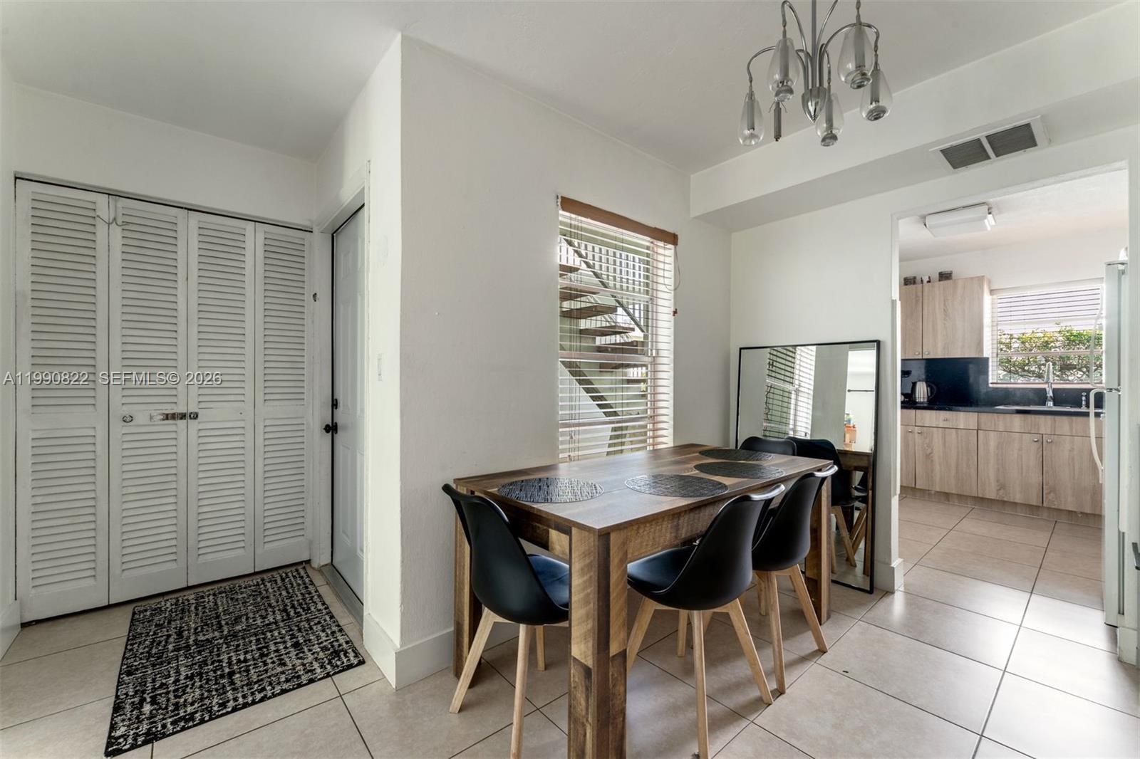 A dining area features a wooden table, black chairs, a chandelier, and a tiled floor — 7670 SW 82nd St # H117, Miami FL 33143, MIAMI, FL