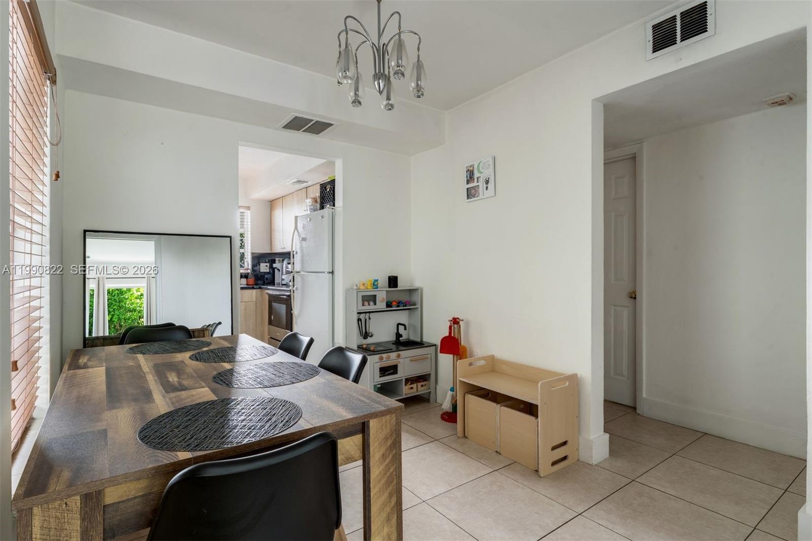 A dining area features a wooden table, black chairs, a play kitchen, and tiled floors — 7670 SW 82nd St # H117, Miami FL 33143, MIAMI, FL
