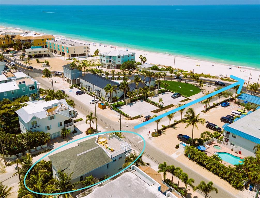 An aerial view shows a multi-story house with a rooftop deck near the beach — 2201 AVENUE C, BRADENTON BEACH, FL