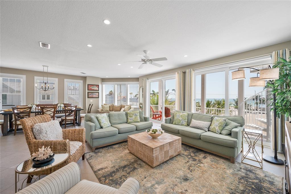 A living room with two green sofas, a wooden coffee table, and ocean views — 2201 AVENUE C, BRADENTON BEACH, FL