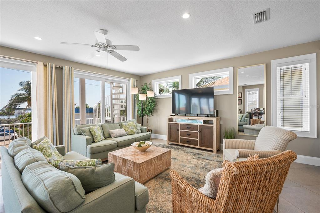 A living room features light green sofas, a wooden coffee table, and a television console — 2201 AVENUE C, BRADENTON BEACH, FL