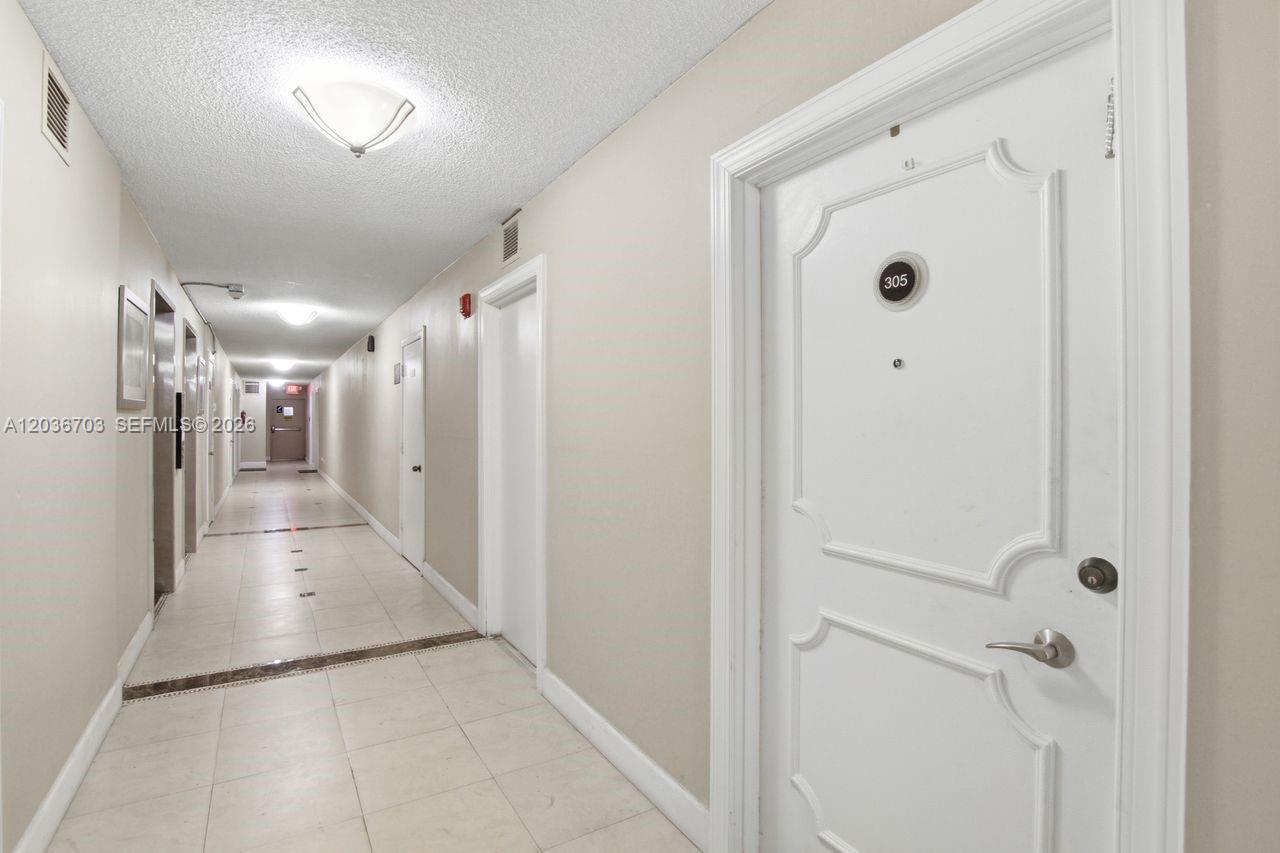 A long, tiled apartment hallway features white doors and recessed ceiling lighting — 1401 S Ocean Dr # 305, Hollywood FL 33019, HOLLYWOOD, FL