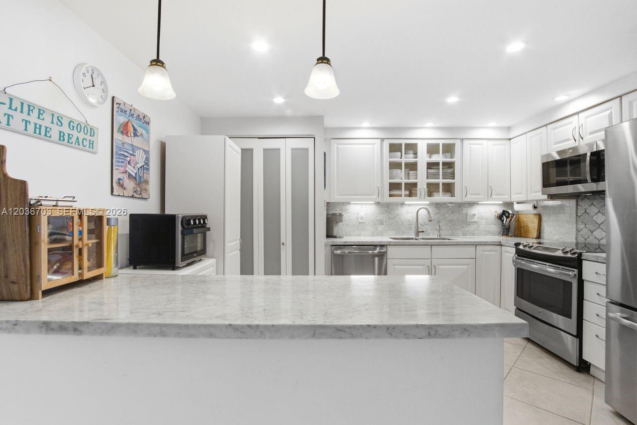 A kitchen features white cabinets, stainless steel appliances, and a marble-topped island — 1401 S Ocean Dr # 305, Hollywood FL 33019, HOLLYWOOD, FL