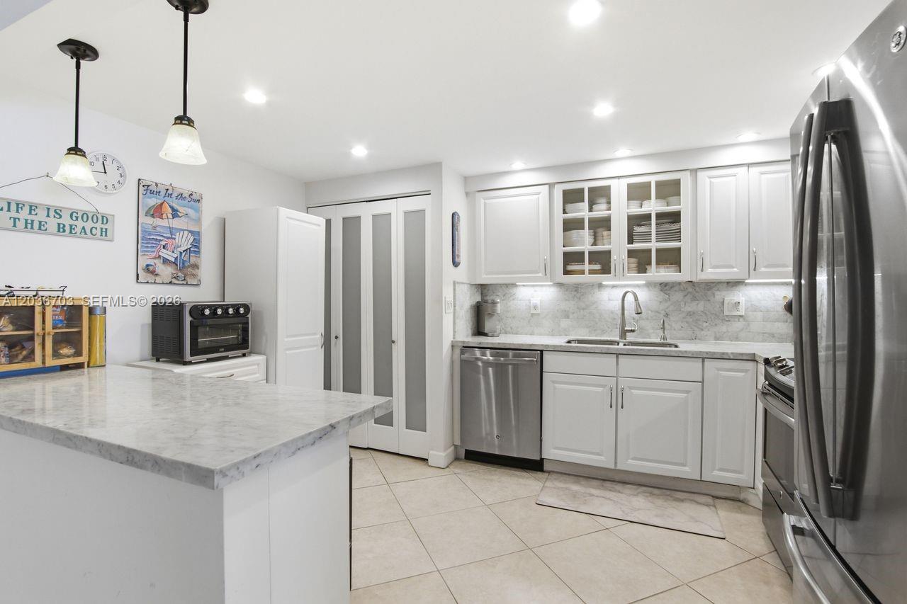 A kitchen features white cabinets, marble countertops, stainless steel appliances, and a tiled floor — 1401 S Ocean Dr # 305, Hollywood FL 33019, HOLLYWOOD, FL