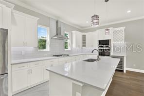 A modern kitchen features white cabinetry, a large quartz island, and stainless steel appliances — 3844 SEENA MANOR COURT, TAMPA, FL