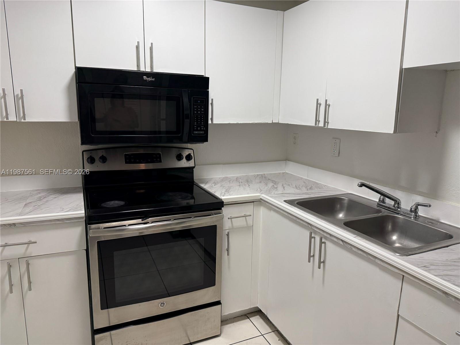 A kitchen features white cabinets, marble-patterned countertops, a stainless steel stove, and a double sink — 5755 W 20th Ave # 201, Hialeah FL 33012, HIALEAH, FL
