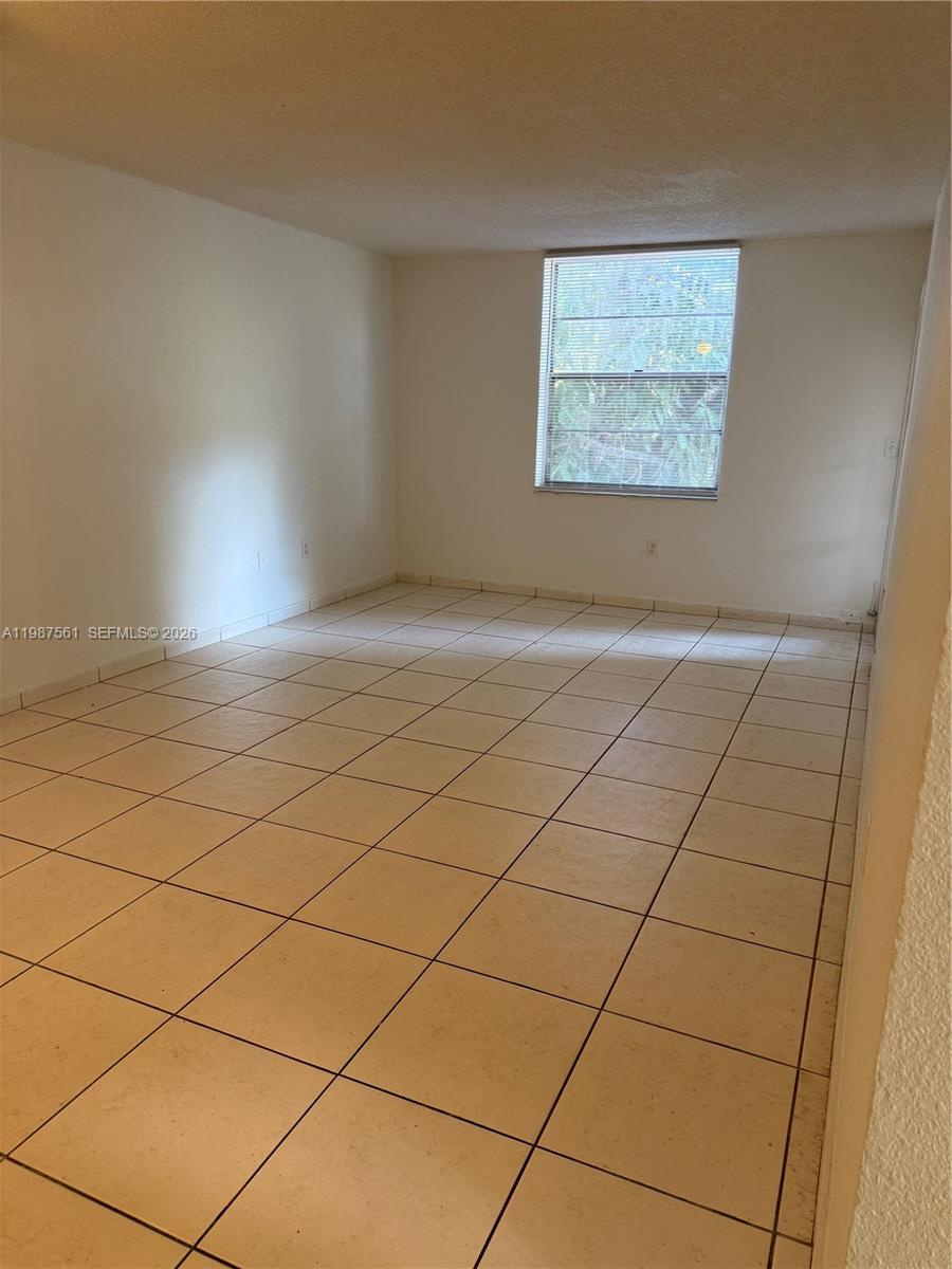 An empty room features beige tile flooring, white walls, and a single window with blinds — 5755 W 20th Ave # 201, Hialeah FL 33012, HIALEAH, FL