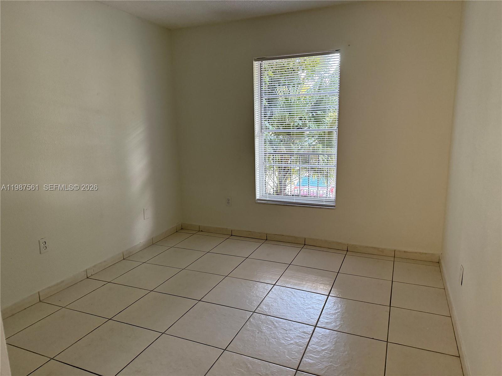 An empty room features light-colored floor tiles, white walls, and a window with blinds — 5755 W 20th Ave # 201, Hialeah FL 33012, HIALEAH, FL