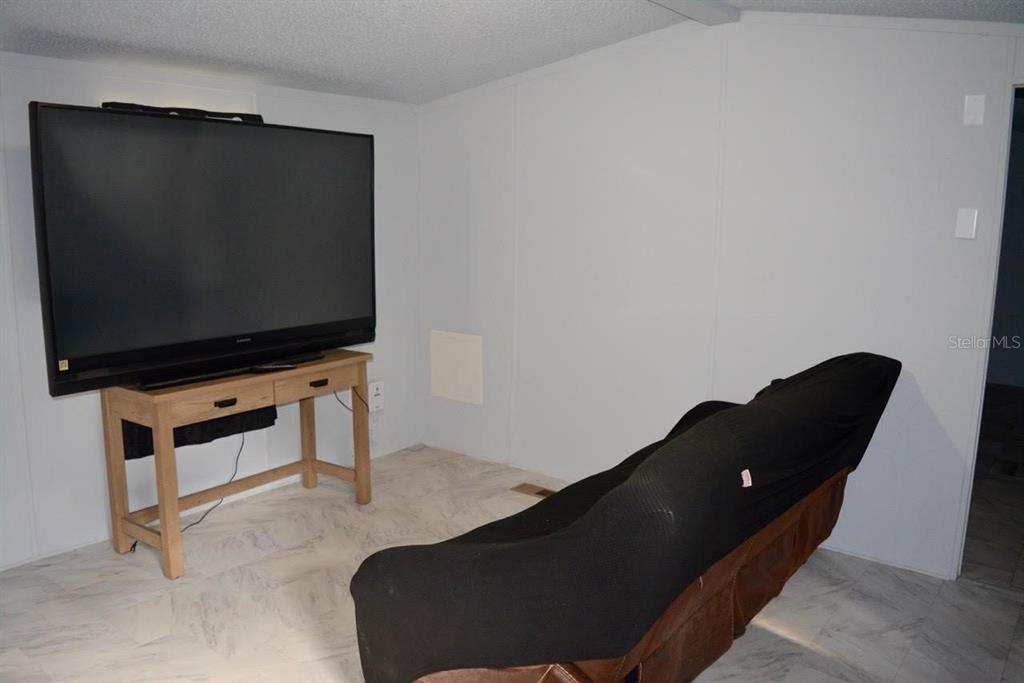 A living room features a large television on a wooden table and a covered sofa — 14350 SE 41ST TERRACE, SUMMERFIELD, FL