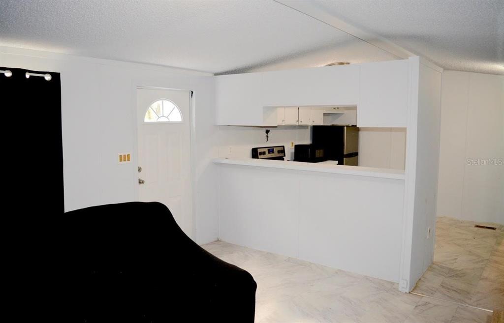 A white kitchen with a breakfast bar overlooks a living area with a black sofa — 14350 SE 41ST TERRACE, SUMMERFIELD, FL