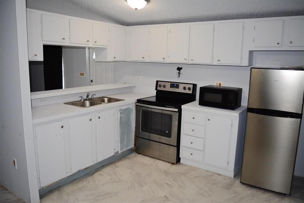 A kitchen with white cabinets, stainless steel appliances, and a double sink on white countertops — 14350 SE 41ST TERRACE, SUMMERFIELD, FL