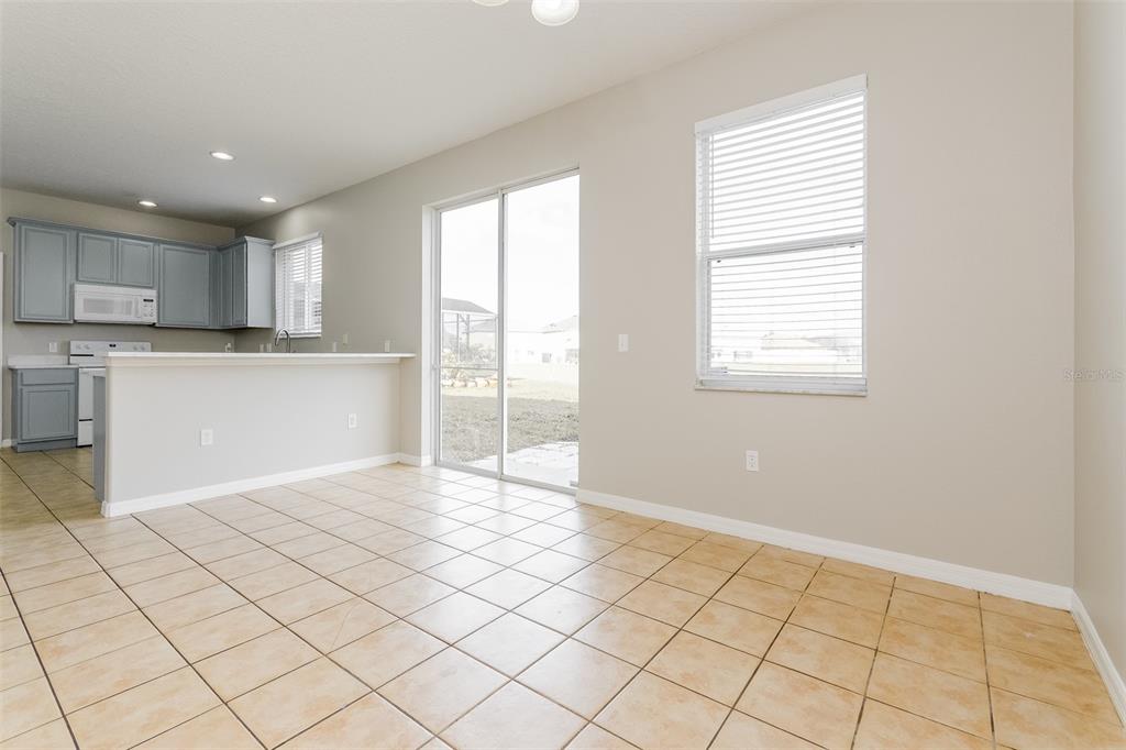 A kitchen with gray cabinets and a dining area featuring tile floors and sliding doors — 513 BERRY JAMES COURT, KISSIMMEE, FL