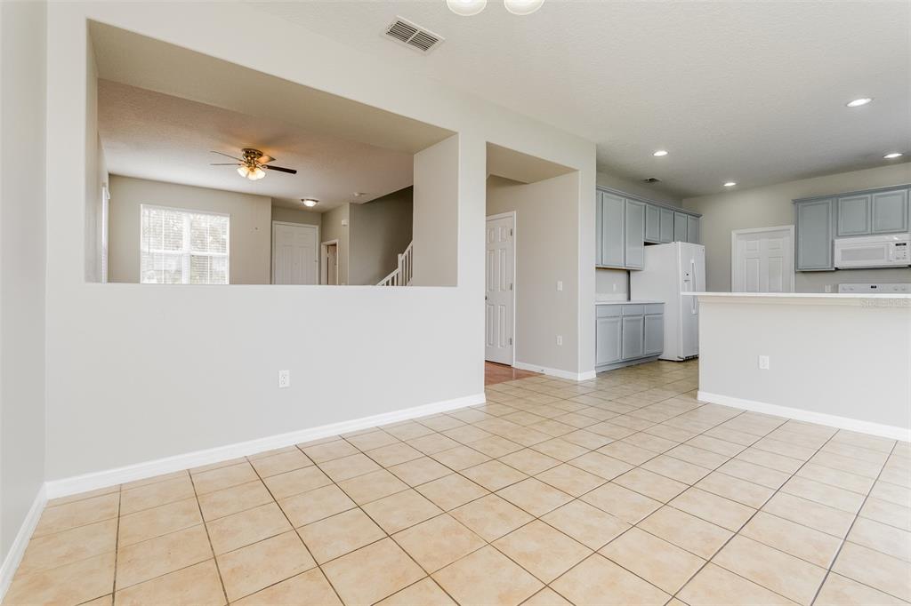 A dining area with tile flooring opens to a kitchen and a living room space — 513 BERRY JAMES COURT, KISSIMMEE, FL