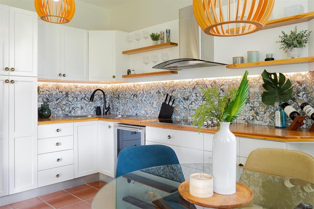A kitchen features white cabinets, wood countertops, a patterned tile backsplash, and two wooden pendant lights — 2901 EL DORADO CLUB UNIT 2901, VEGA ALTA, PR