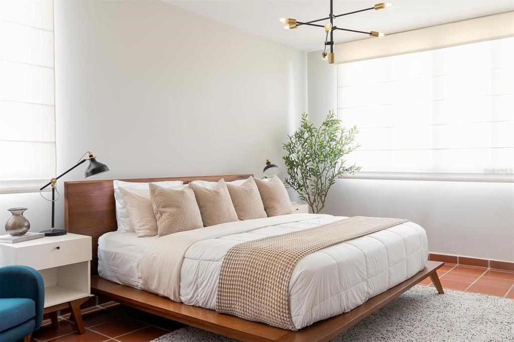 A bedroom features a wooden platform bed, a modern chandelier, and a potted olive tree — 2901 EL DORADO CLUB UNIT 2901, VEGA ALTA, PR