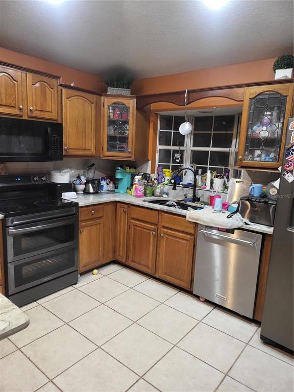 A kitchen features wood cabinets, a black stove, a stainless dishwasher, and tile flooring — 5491 NW OAK HILL AVENUE, ARCADIA, FL