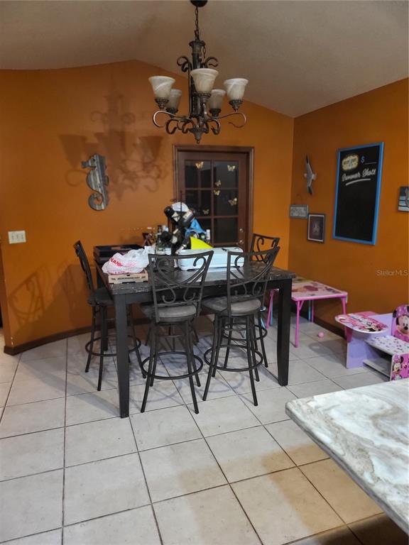 A dining area features a dark table with bar stools, orange walls, and tile flooring — 5491 NW OAK HILL AVENUE, ARCADIA, FL