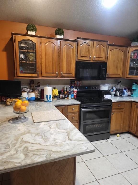 A kitchen features wood cabinets, a black stove, and a marble-patterned countertop — 5491 NW OAK HILL AVENUE, ARCADIA, FL