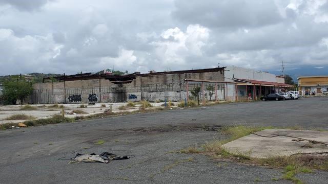 A large, dilapidated commercial building with graffiti and a vast, empty asphalt parking lot — PR-116 INT. PR-121, YAUCO, PR