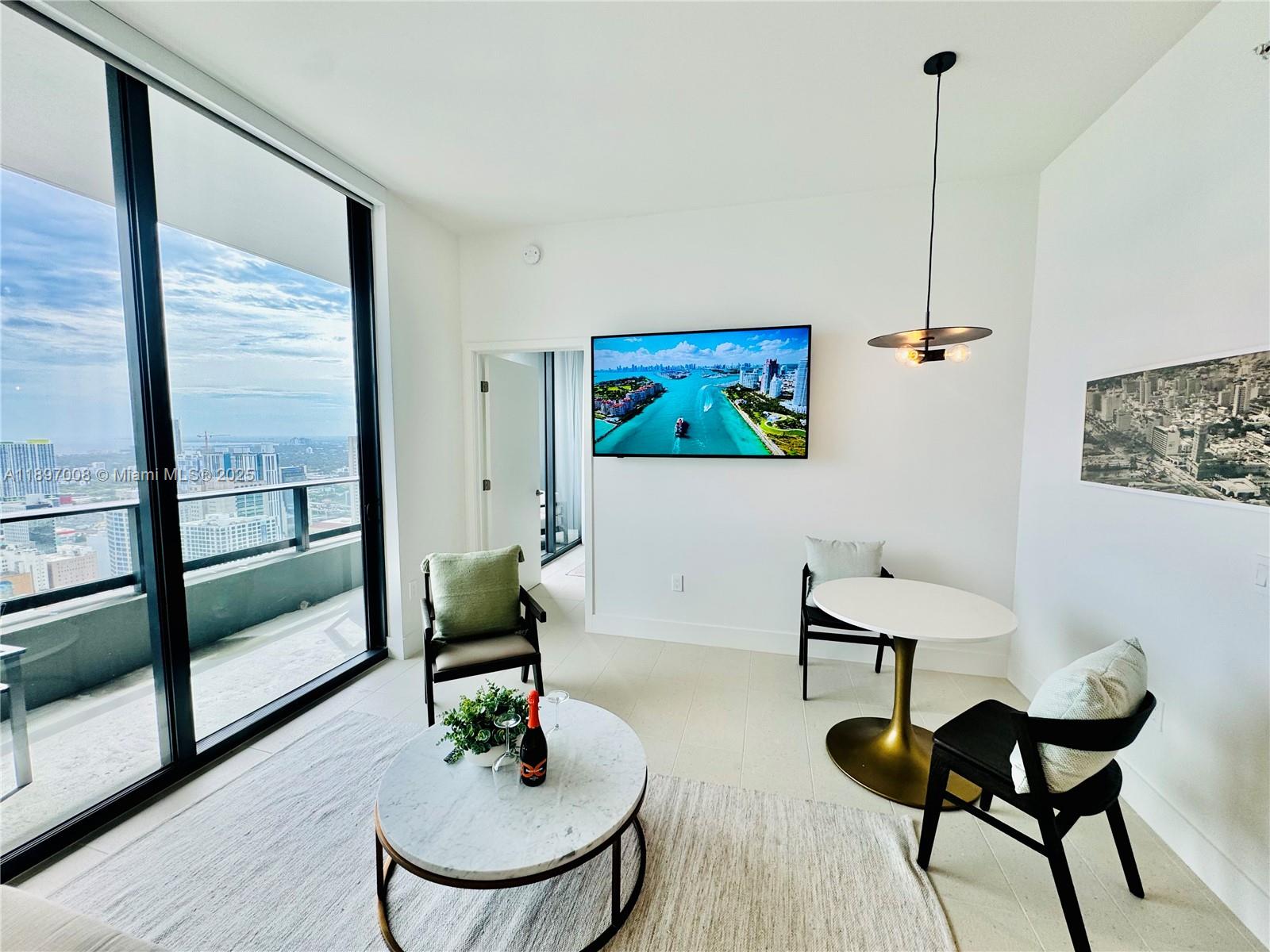 A modern living area features a marble coffee table, dining set, and floor-to-ceiling windows — 159 NE 6th St # 4807, Miami FL 33132, MIAMI, FL