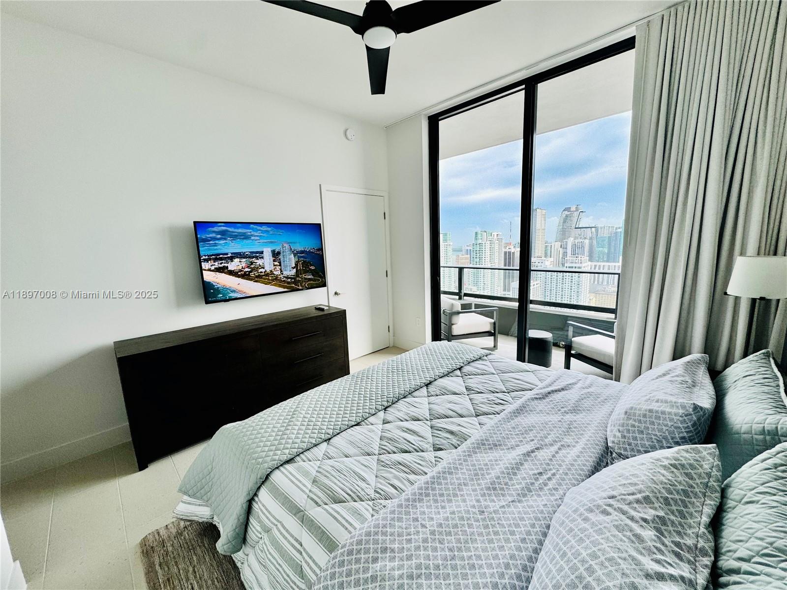 A bedroom features a bed, a wall-mounted television, and a balcony with city views — 159 NE 6th St # 4807, Miami FL 33132, MIAMI, FL