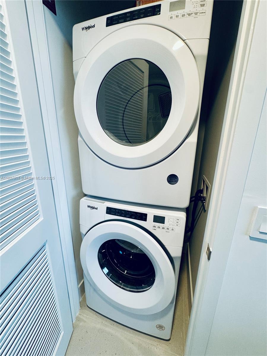 A white stacked Whirlpool washer and dryer unit is installed in a small laundry closet — 159 NE 6th St # 4807, Miami FL 33132, MIAMI, FL