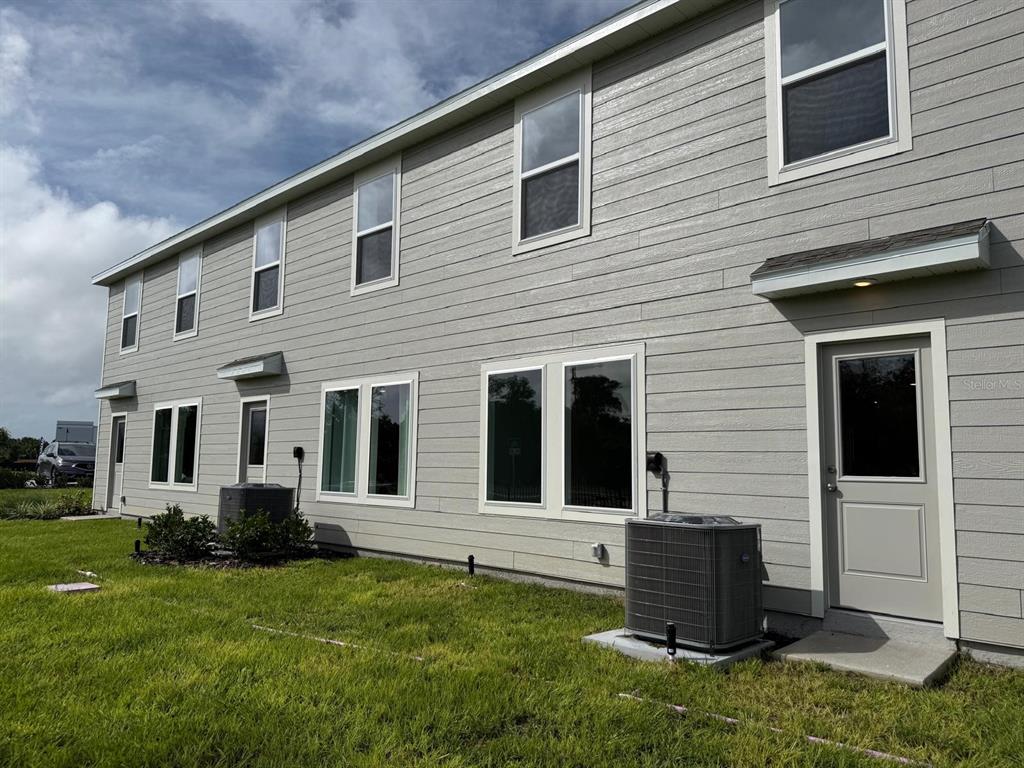 The exterior of a two-story gray house features horizontal siding, multiple windows, and two air-conditioning units — 1231 ORION ST, DAVENPORT, FL