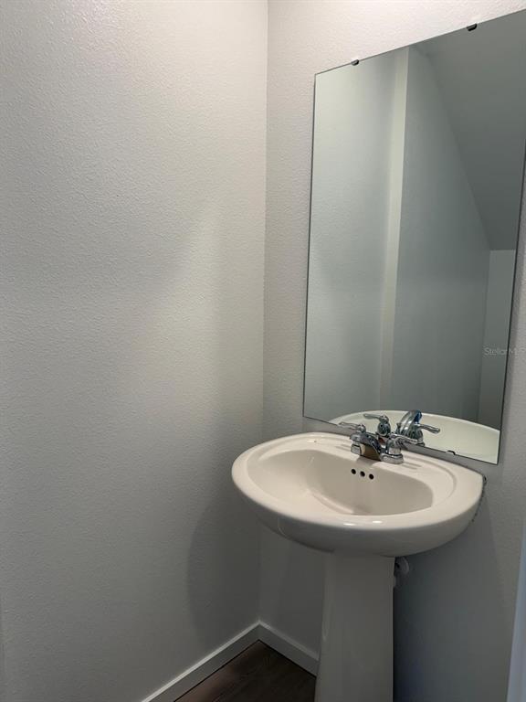 A white pedestal sink with a chrome faucet sits below a rectangular wall mirror — 1231 ORION ST, DAVENPORT, FL