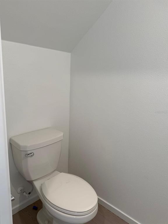 A white toilet is positioned in a small, plain bathroom with light-colored walls and flooring — 1231 ORION ST, DAVENPORT, FL