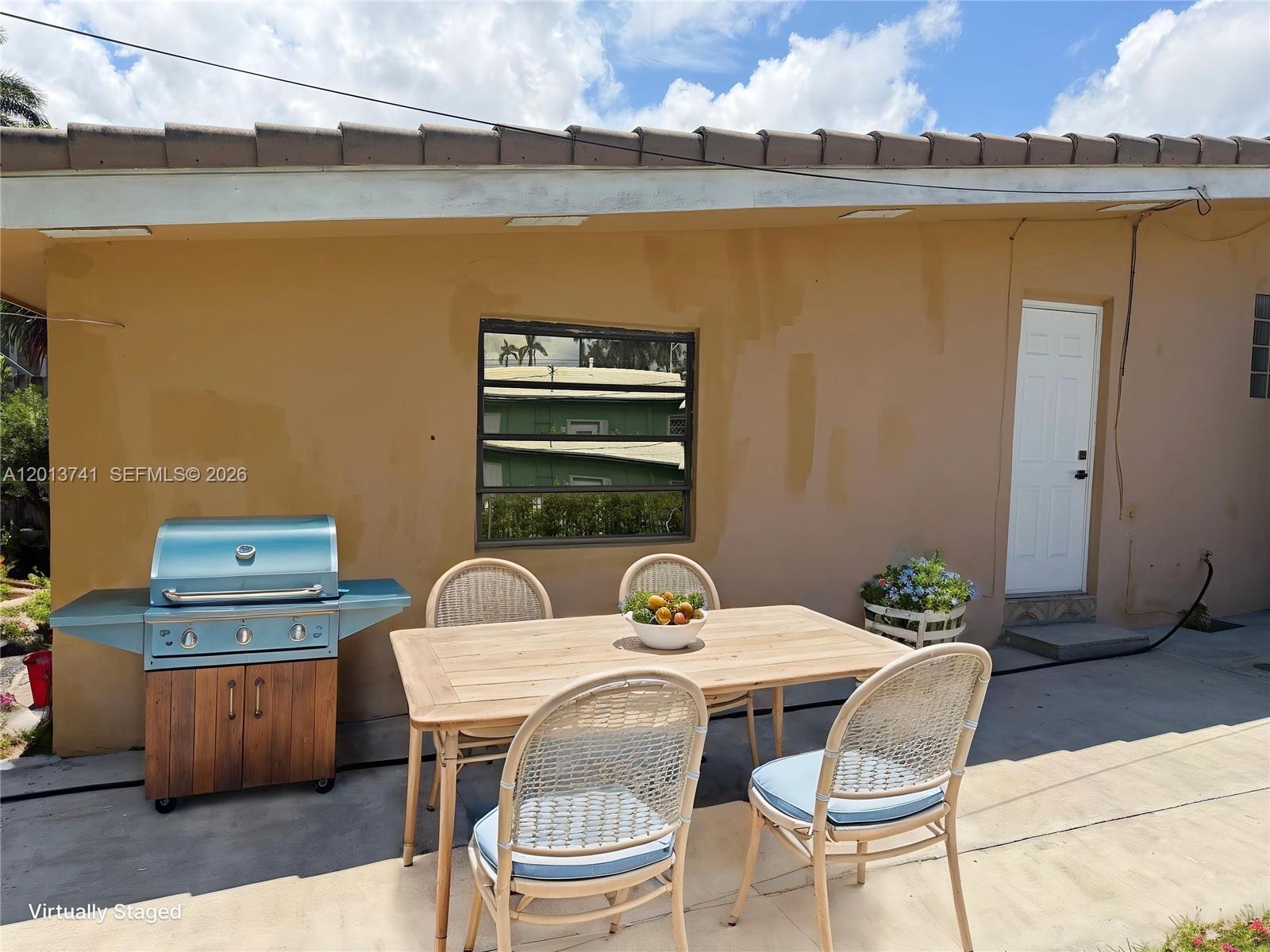 An outdoor patio features a grill, a wooden dining table, and four chairs — HOLLYWOOD, FL