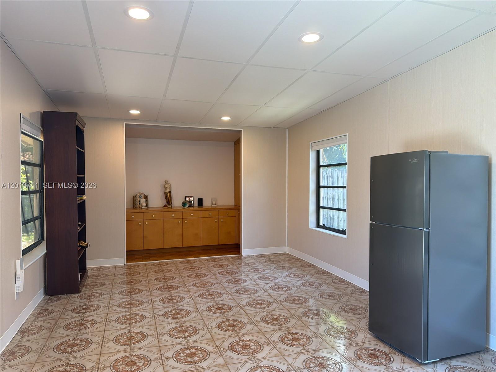 A room with patterned tile flooring, a built-in cabinet, a dark bookshelf, and a refrigerator — HOLLYWOOD, FL