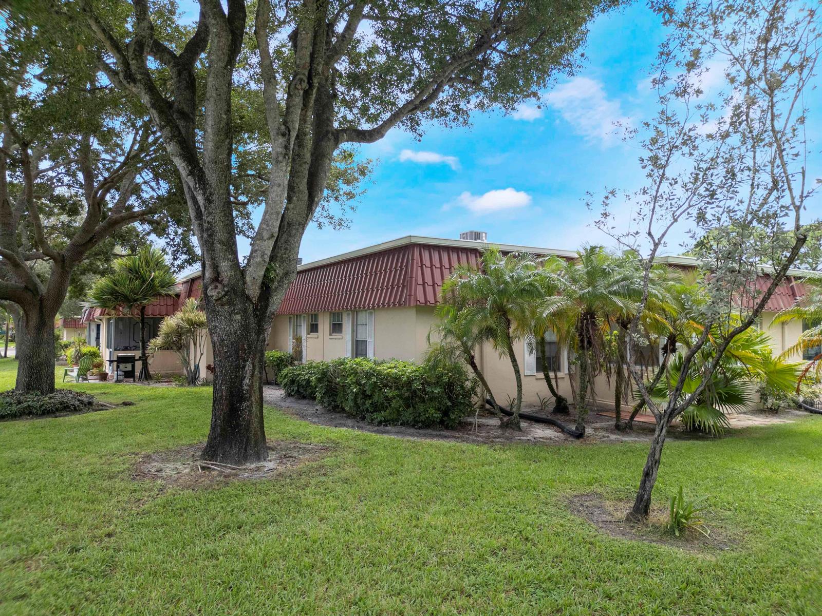 A tan single-story building with a red mansard roof sits on a grassy lawn — 857 Worcester Lane # B, Lake Worth FL 33467, LAKE WORTH, FL