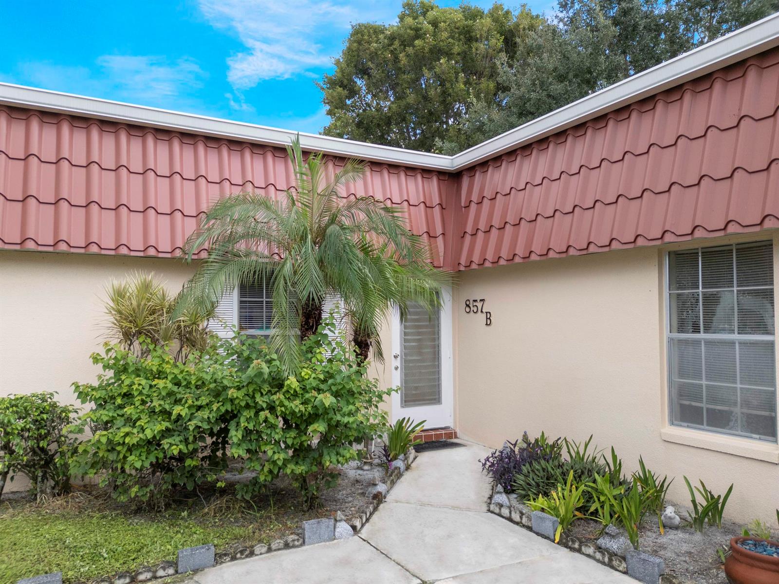 The exterior of a single-story home features a red metal roof and a front walkway — 857 Worcester Lane # B, Lake Worth FL 33467, LAKE WORTH, FL