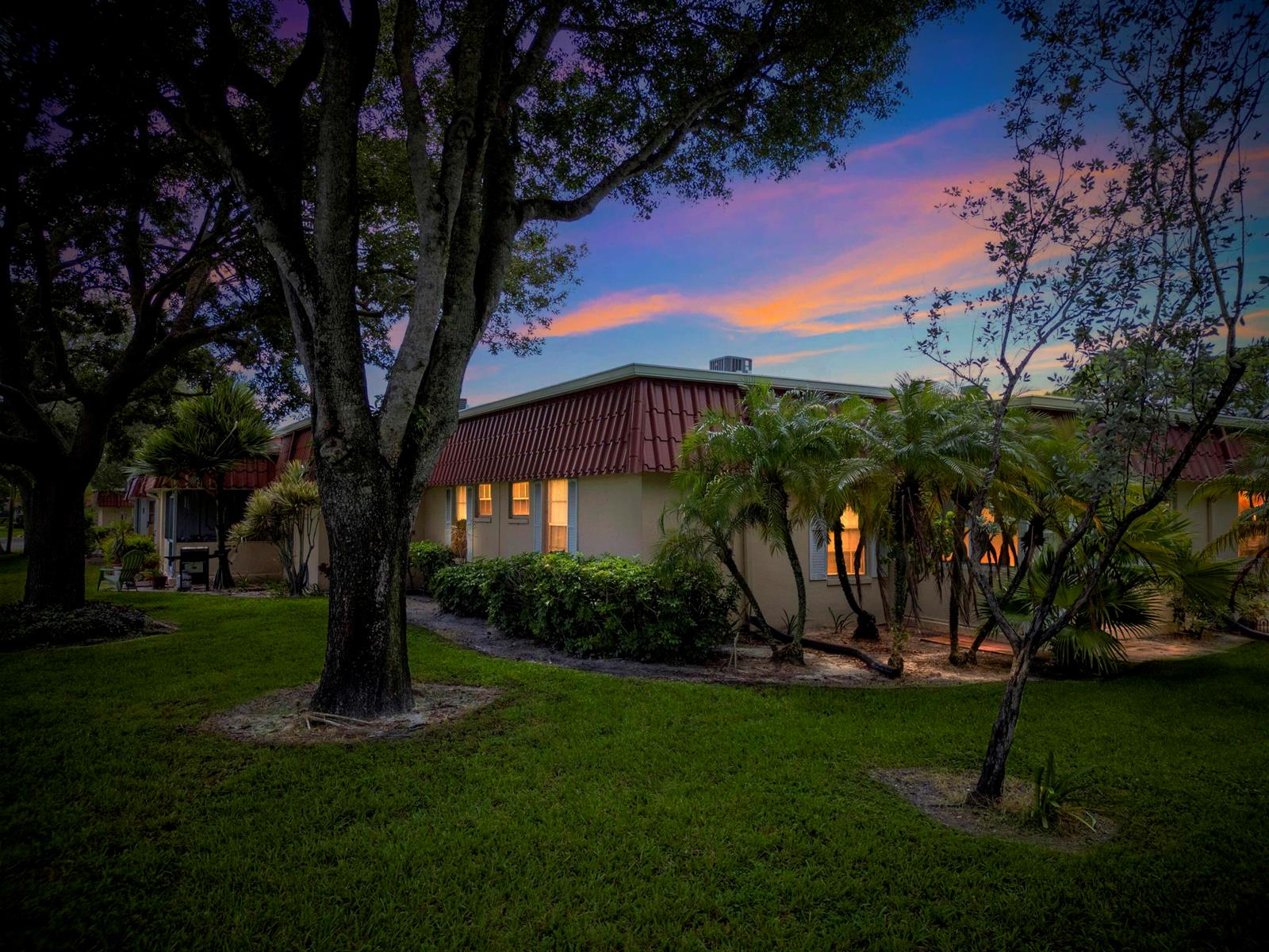 A single-story house with a red tile roof surrounded by trees and landscaping at sunset — 857 Worcester Lane # B, Lake Worth FL 33467, LAKE WORTH, FL