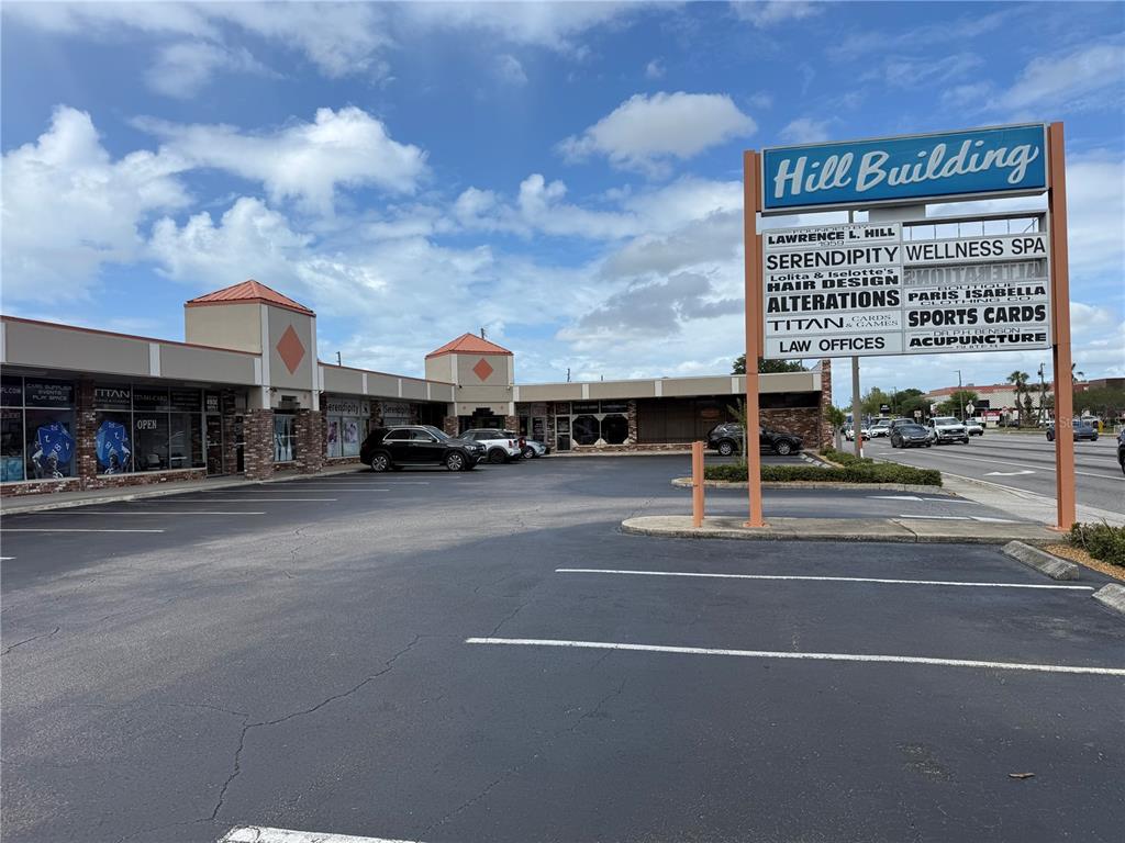 A low-rise commercial strip mall with a large freestanding sign stands in a parking lot — 4930 PARK BOULEVARD N UNIT 1, PINELLAS PARK, FL