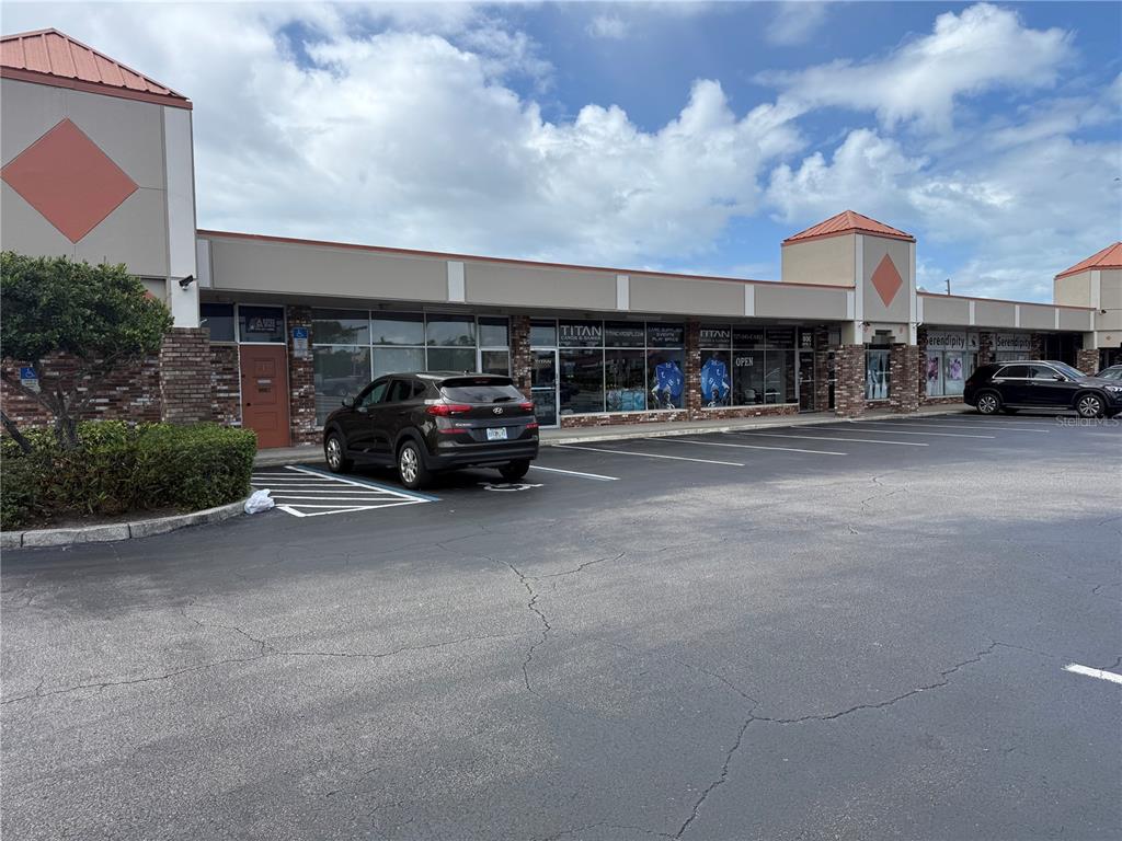 A commercial strip mall building features a parking lot with a parked SUV — 4930 PARK BOULEVARD N UNIT 1, PINELLAS PARK, FL