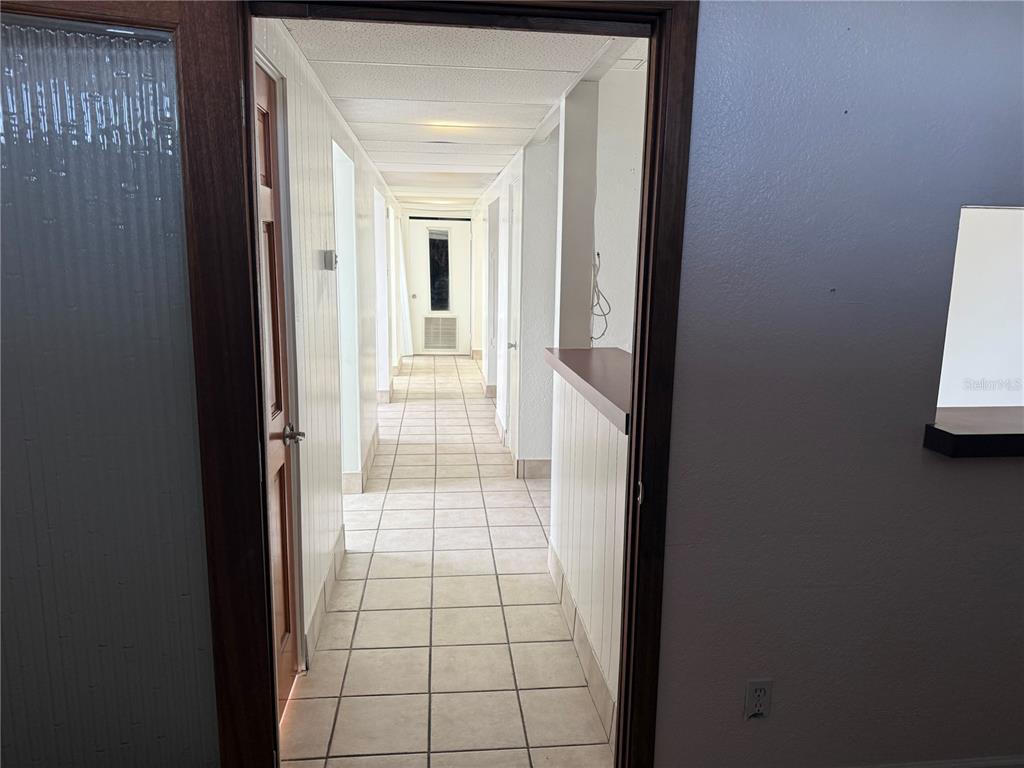 A tiled hallway leads to a door at the end, flanked by white walls — 4930 PARK BOULEVARD N UNIT 1, PINELLAS PARK, FL