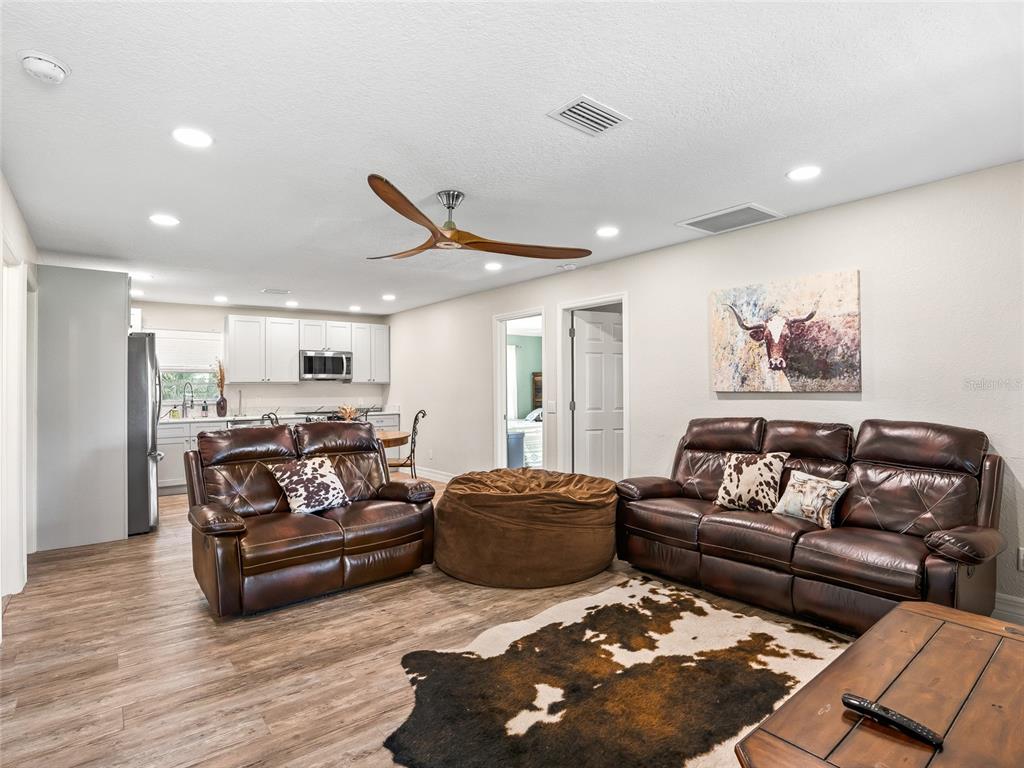 A living room with brown leather furniture, a cowhide rug, and an open kitchen — 10291 W HIGHWAY 40, OCALA, FL