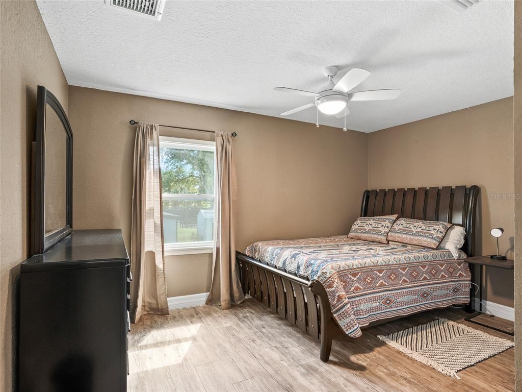 A bedroom features a wooden bed frame, a black dresser, and wood-look flooring — 10291 W HIGHWAY 40, OCALA, FL