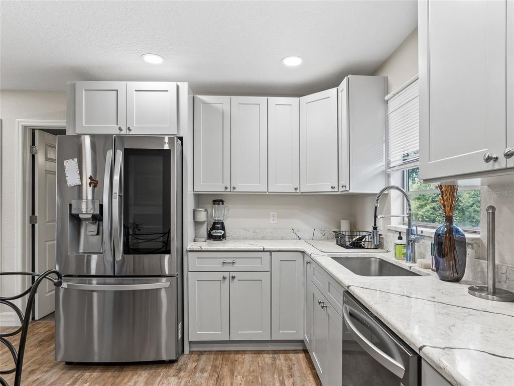 A kitchen features light gray cabinets, stainless steel appliances, and white marble-patterned countertops — 10291 W HIGHWAY 40, OCALA, FL