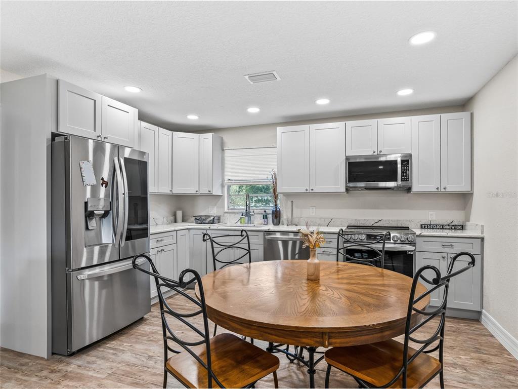 A kitchen features light gray cabinets, stainless steel appliances, and a round wooden dining table — 10291 W HIGHWAY 40, OCALA, FL
