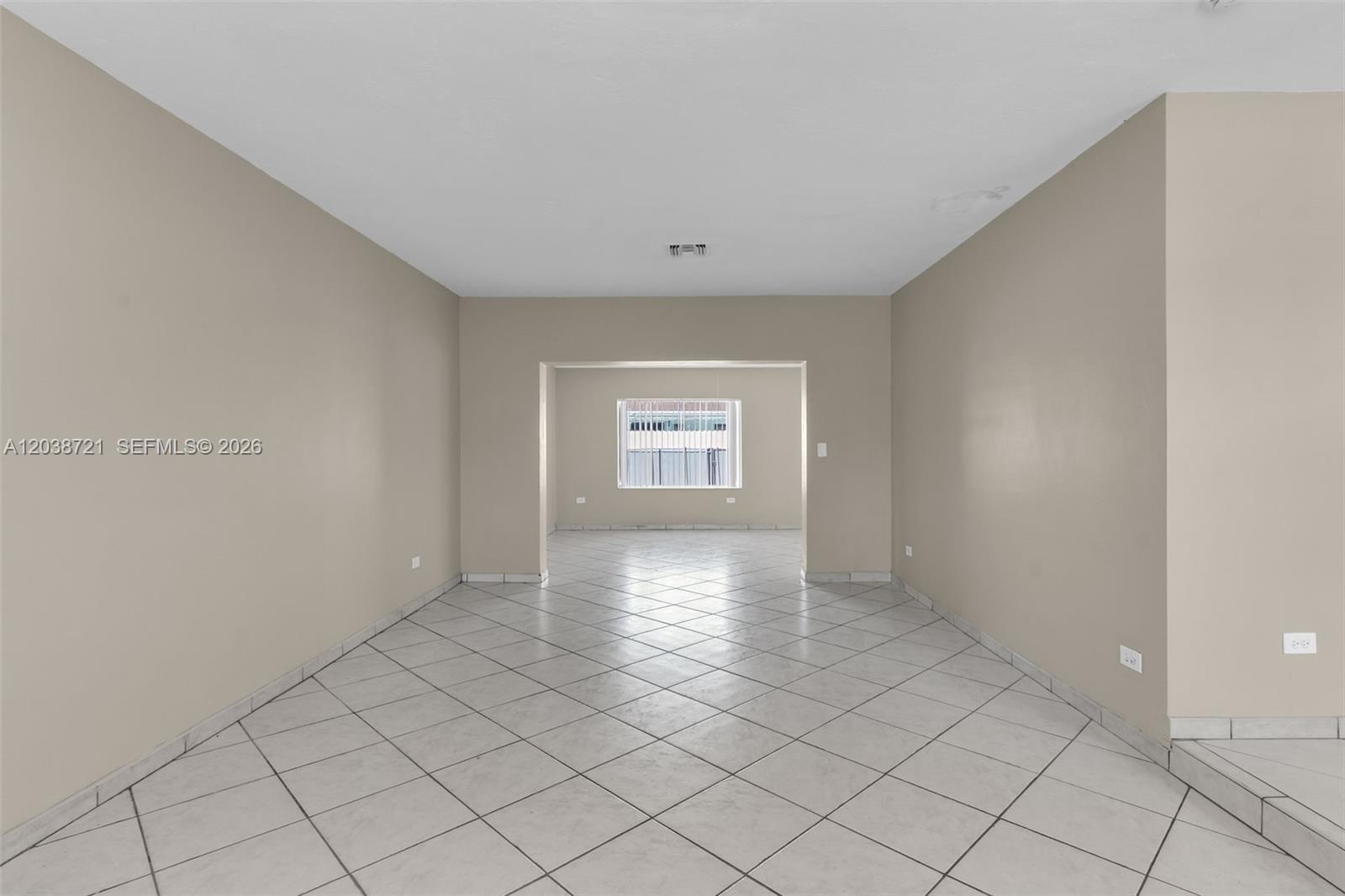 An empty room with light-colored tile flooring and beige walls leads to a smaller area — 1720 SW 98th Ct, Miami FL 33165, MIAMI, FL
