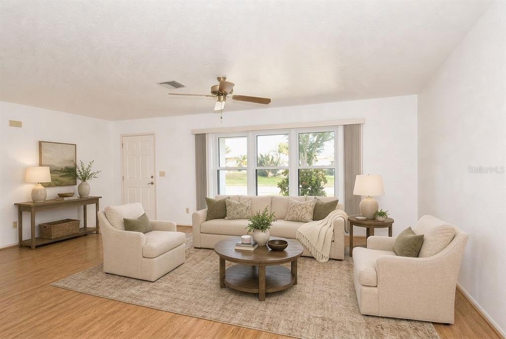 A living room features a beige sofa, two armchairs, a coffee table, and wood flooring — 1379 EVEREST ROAD, VENICE, FL