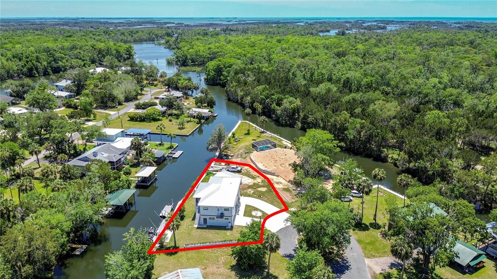 An aerial view shows a white house on a waterfront lot surrounded by trees — 25 PALM DRIVE, YANKEETOWN, FL