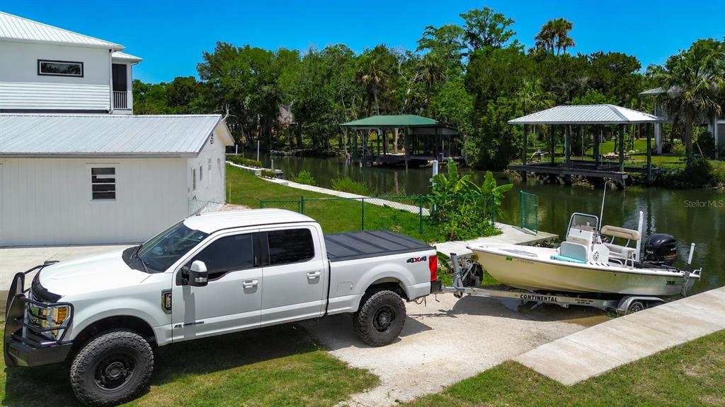 A white pickup truck is parked on a concrete ramp, towing a boat near a canal — 25 PALM DRIVE, YANKEETOWN, FL