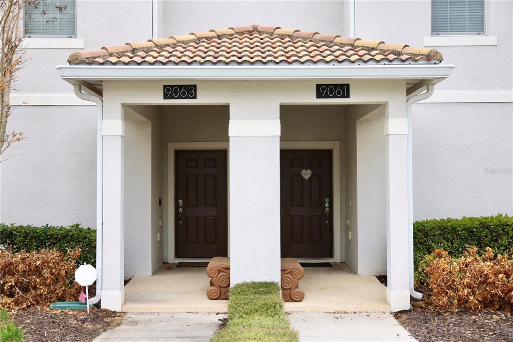 The exterior of a building features two adjacent front doors under a shared roof — 9063 DOGLEG DRIVE, DAVENPORT, FL