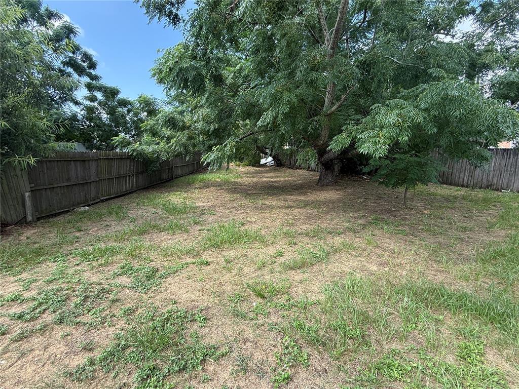 A large, grassy backyard is enclosed by a wooden fence and features a mature tree — 7425 VILLAS OAK COURT, ORLANDO, FL