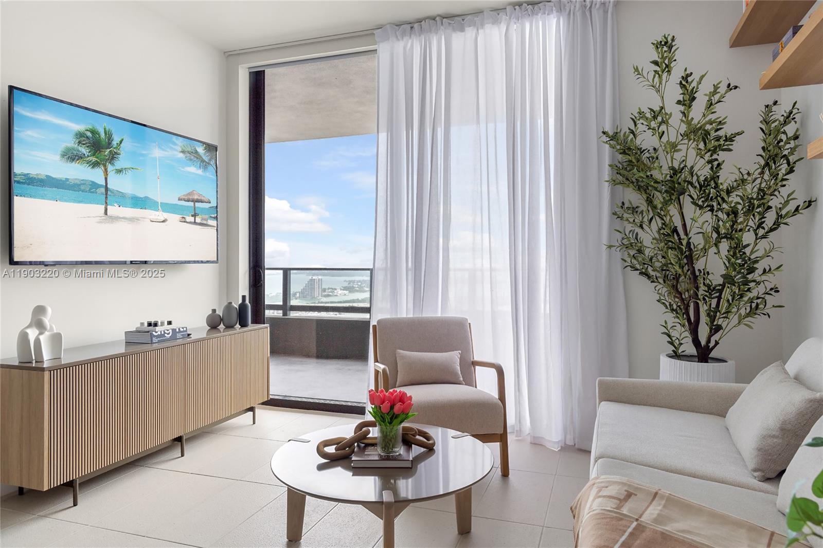 A modern living room features a television, a balcony with water views, and neutral furniture — 159 NE 6th St # 3615, Miami FL 33132, MIAMI, FL