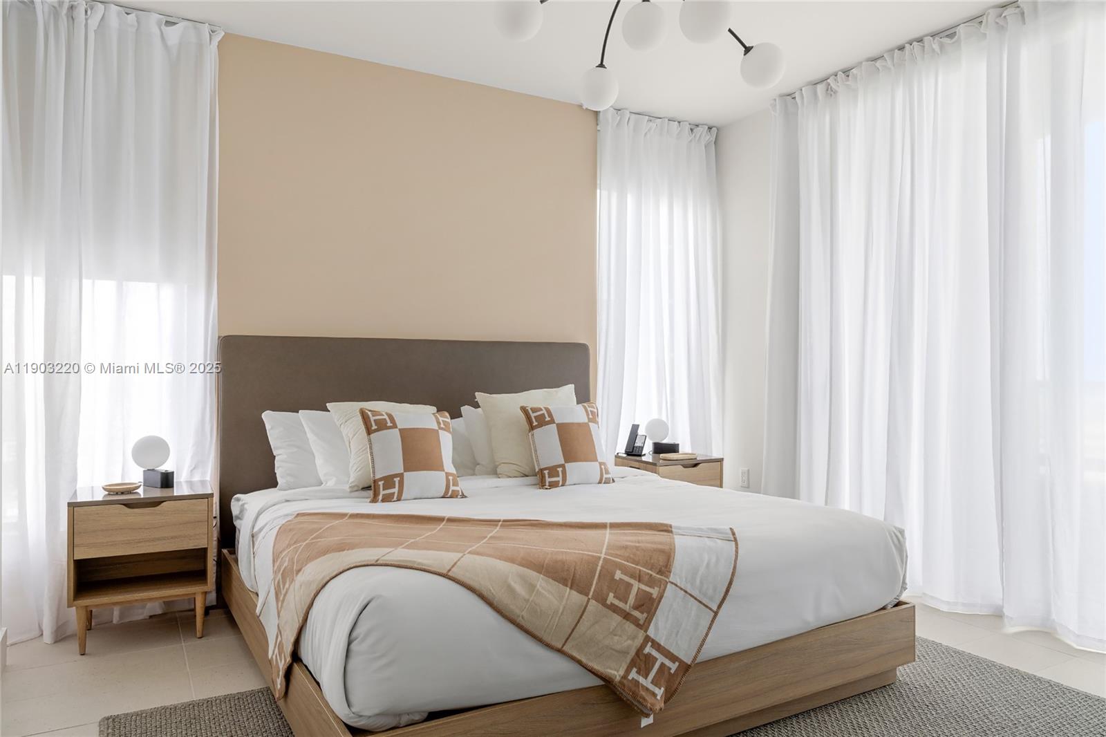 A bedroom features a platform bed with tan bedding against a beige accent wall — 159 NE 6th St # 3615, Miami FL 33132, MIAMI, FL