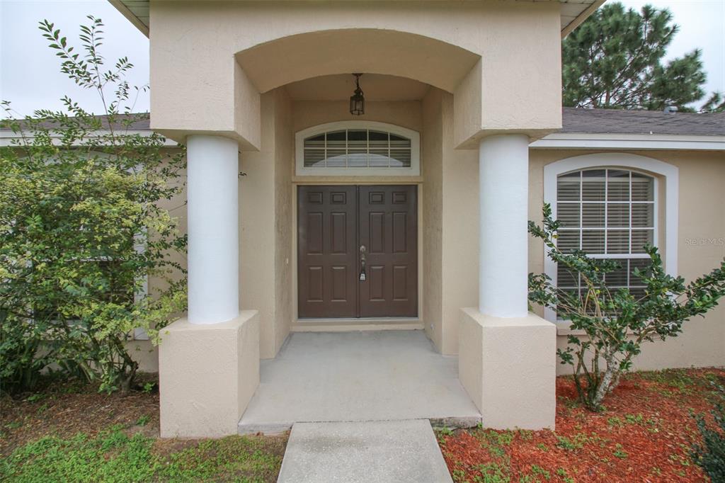 The front entrance features a concrete walkway leading to double doors under a covered porch — 3002 CHASEWOOD DRIVE, LAKELAND, FL